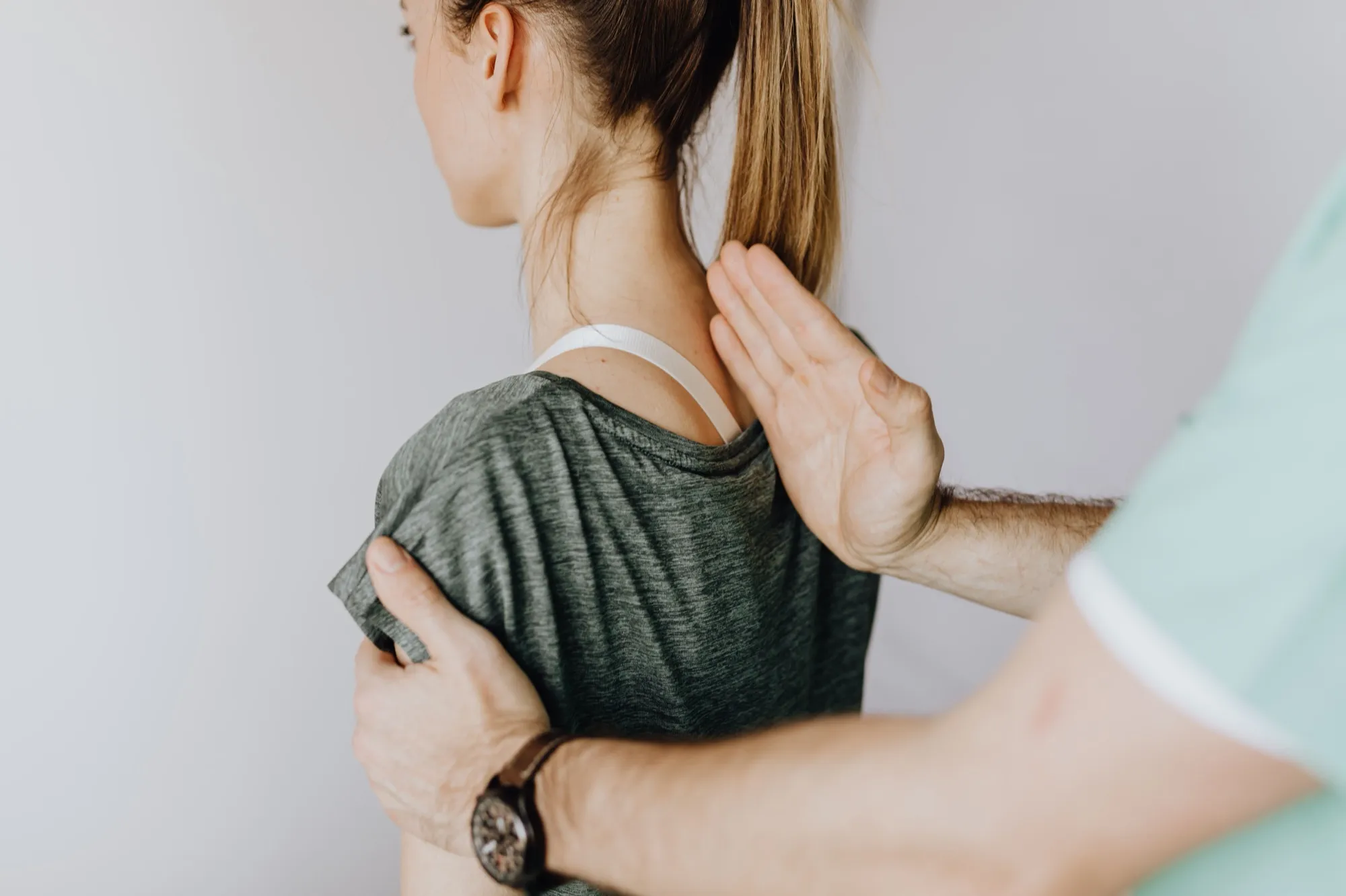 A Doctor of Physical Therapy assessing a patient's shoulder during a home visit
